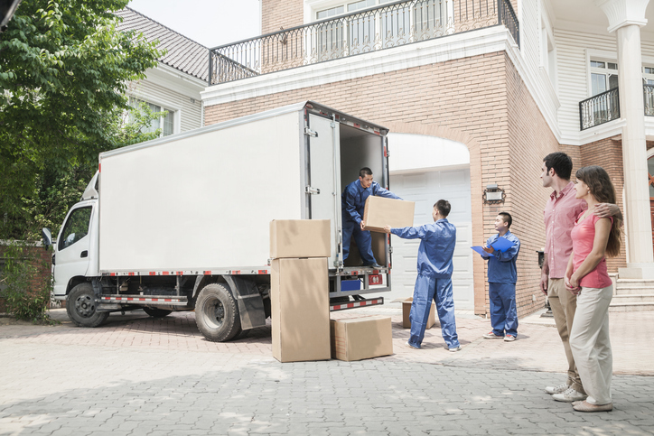 Young couple watching movers move boxes from the moving van and they are stressed out over the move.